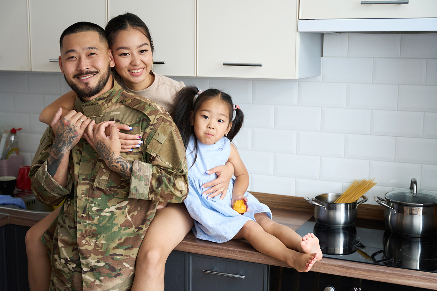 Woman hugging her military husband and little daughter