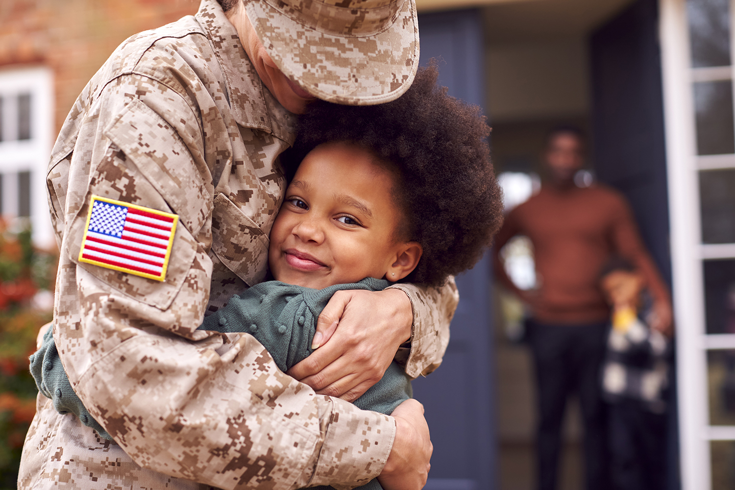 American Female Soldier In Uniform hugging little boy