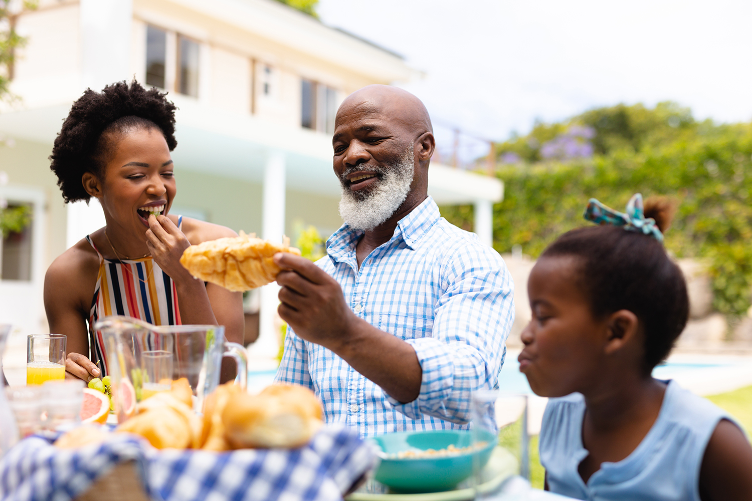 Smiling bald bearded african american senior man enjoying brunch with family at backyard. family, love and togetherness concept, unaltered.