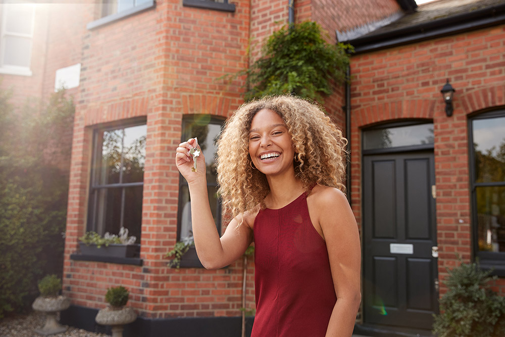 Smiling woman outside of house holding keys